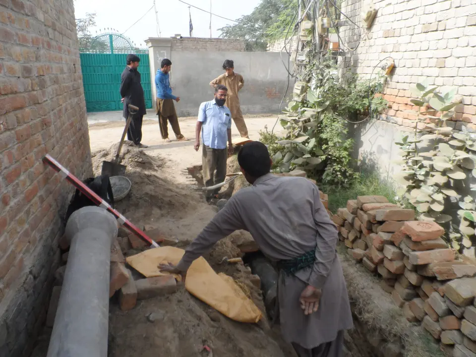 Residents and workers laying a sewer pipe in a narrow lane