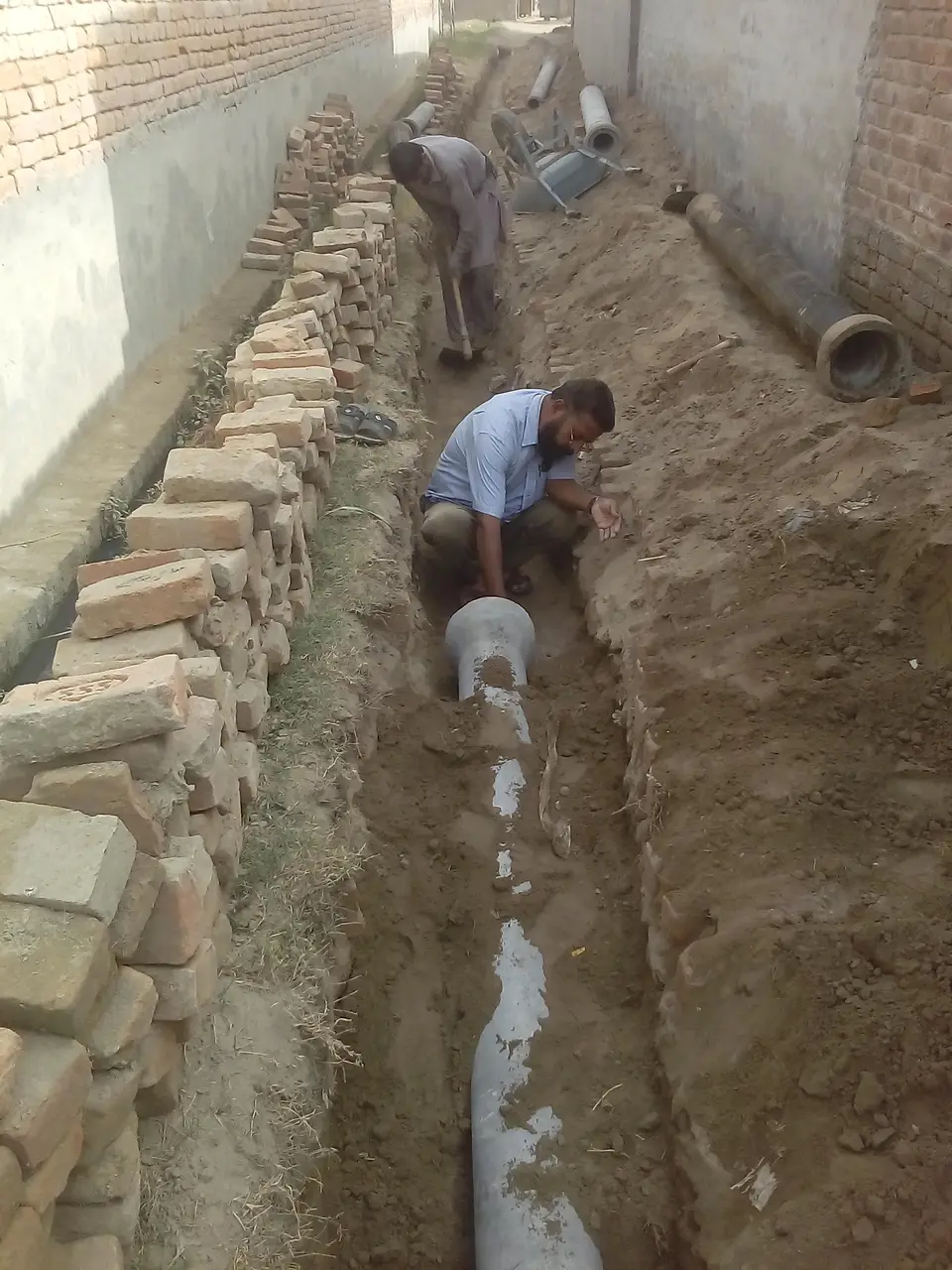 نئی کھدی خندق میں پائپ بچھانا۔