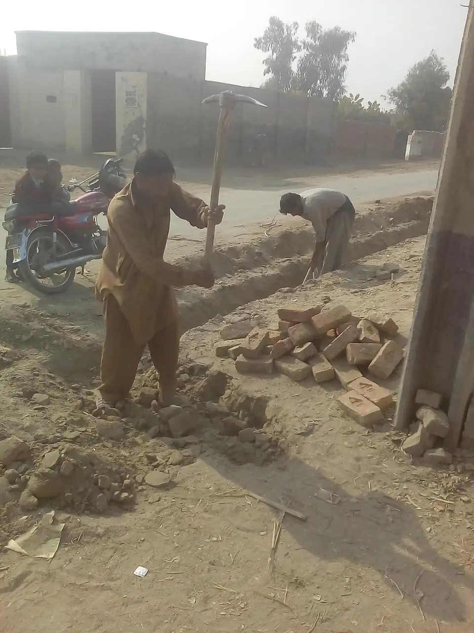 گلی کی نالی ہاتھ سے کھودتے ہوئے۔