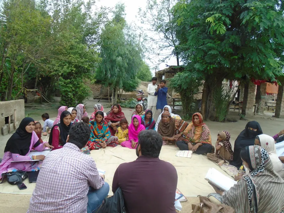 Women of a saving group meeting outdoors in a village