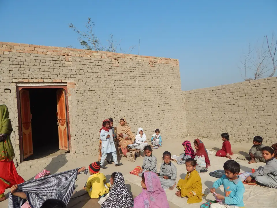 گاؤں کے صحن میں سبق کے لیے بیٹھے بچے