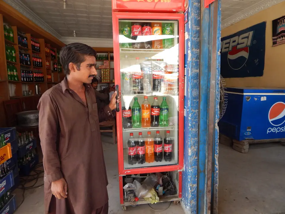 A shopkeeper beside his drinks fridge in his general store